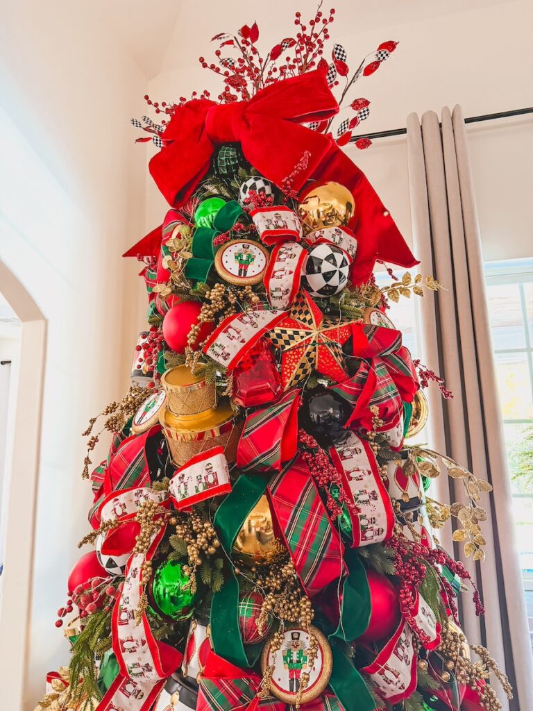 top half of a chrismtas tree with red bow topper and red green and gold ornaments