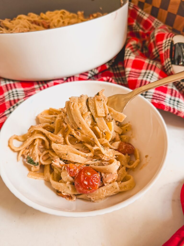 salmon pasta bake in a white bowl with a fork 