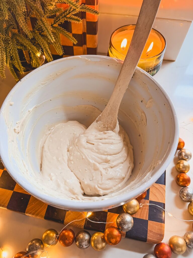 Greek yogurt base being mixed in a white bowl with a wooden spoon.