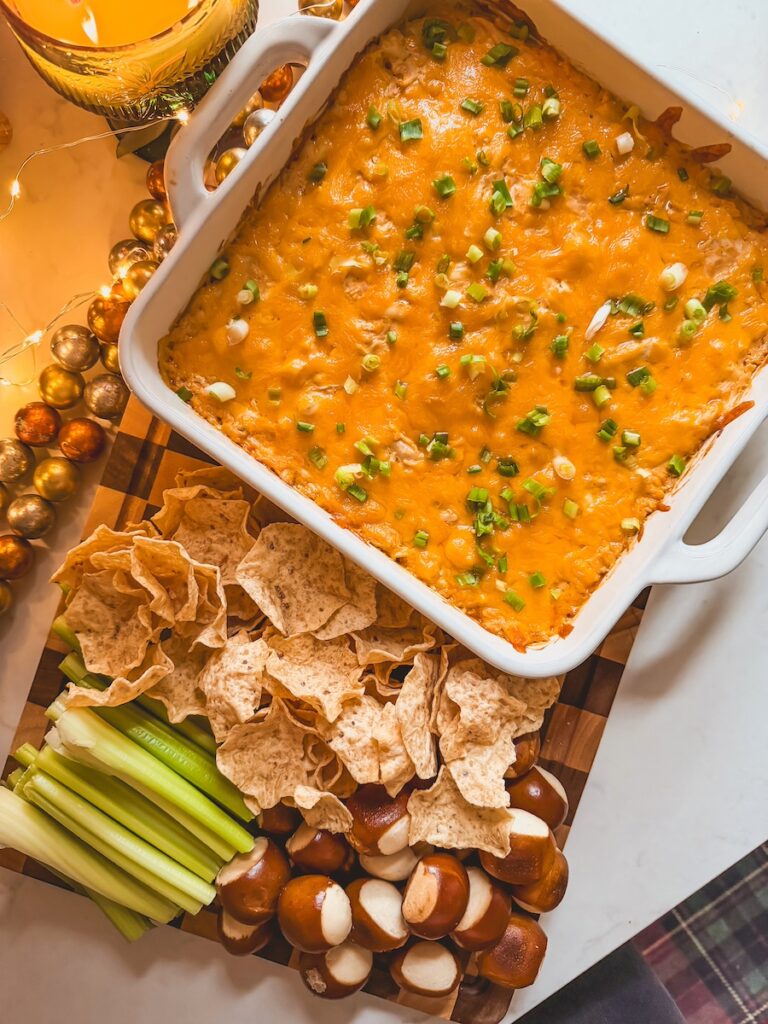 Baked Greek yogurt buffalo chicken dip on a board with dippers.