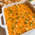 Close up view of Greek yogurt buffalo chicken dip on a board with chips in the background.