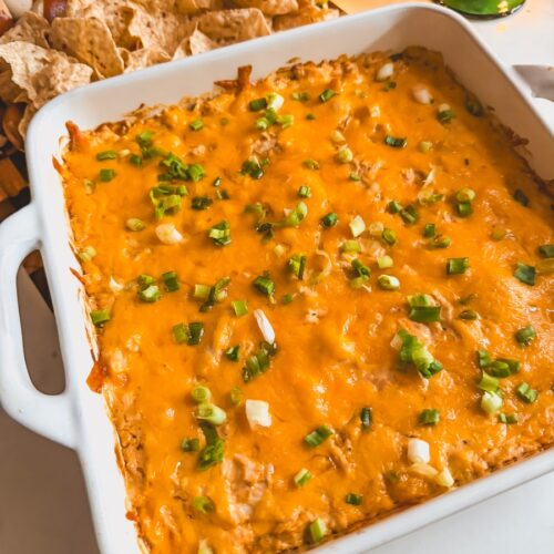 Close up view of Greek yogurt buffalo chicken dip on a board with chips in the background.