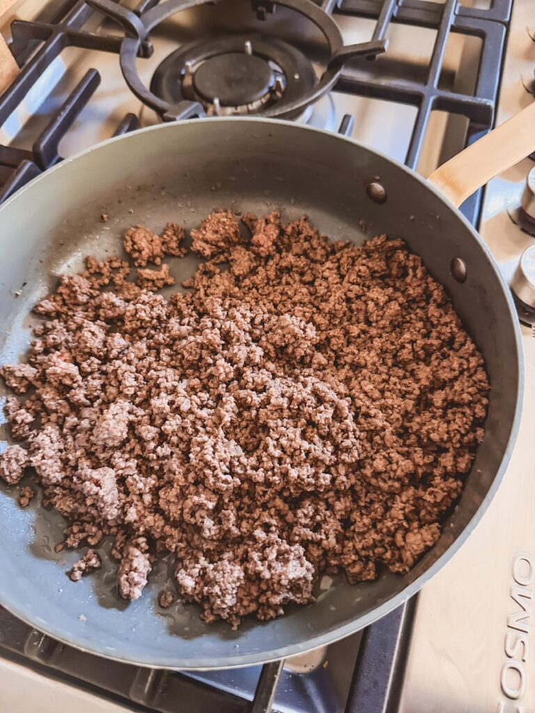 Ground beef in a large skillet on the stovetop.