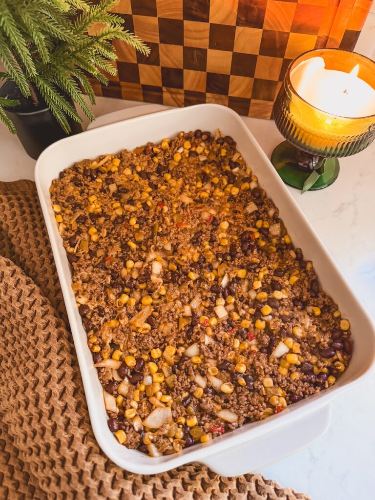The ground beef, bean, and corn mixture pressed into a baking dish.