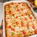 Mexican tater tot casserole with scallions and cherry tomatoes on top.