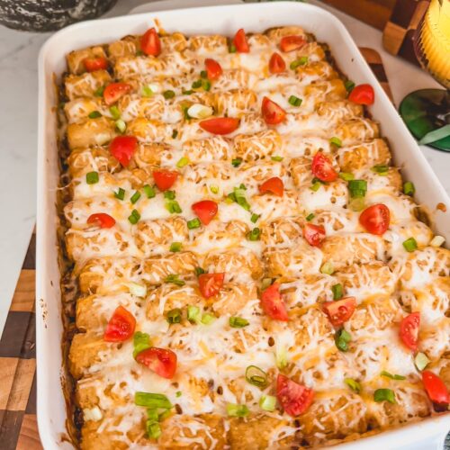 Mexican tater tot casserole with scallions and cherry tomatoes on top.