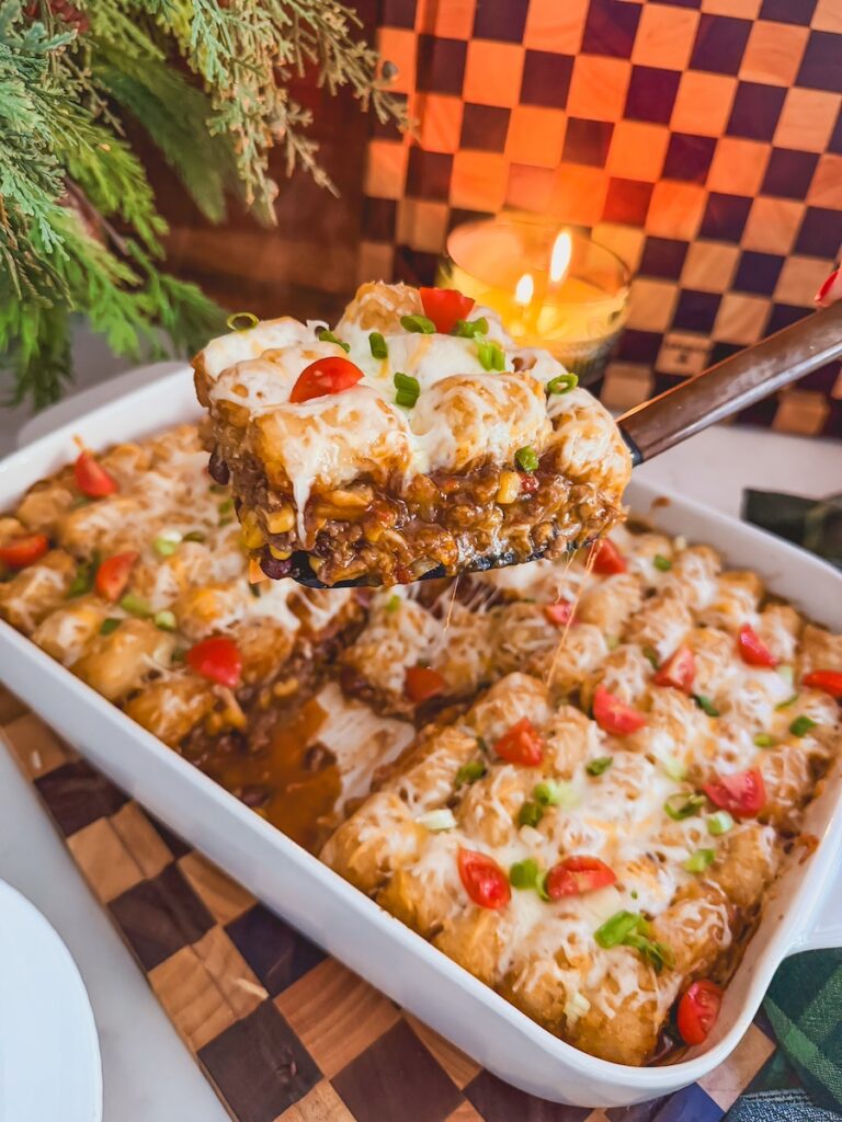 A metal spatula scooping out a serving of Mexican tater tot casserole.