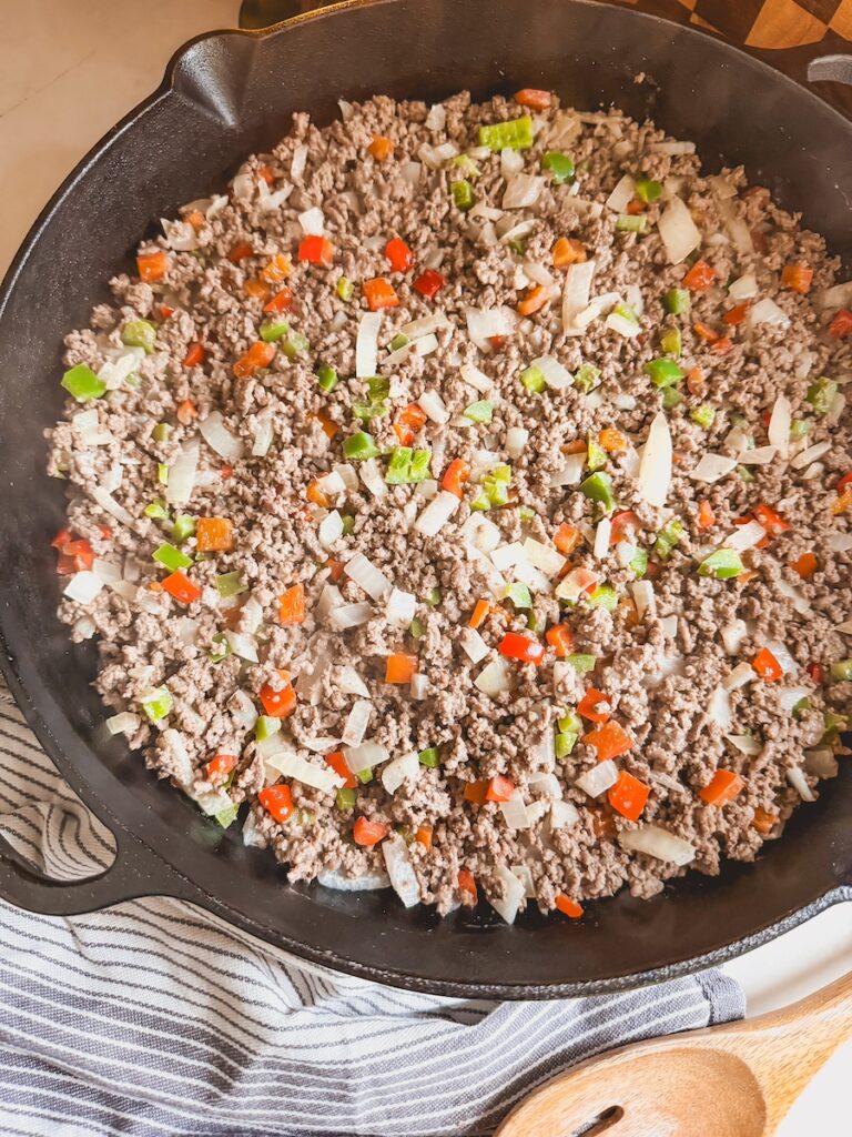 A cast iron pan with ground beef peppers and onions.