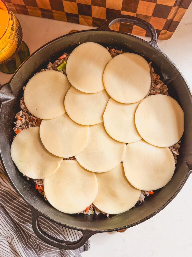 Slices of provolone cheese on top of the philly cheesesteak casserole beef filling.