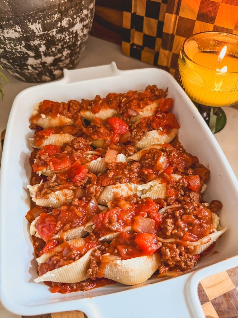 Stuffed shells with meat and tomato sauce in a white baking dish.