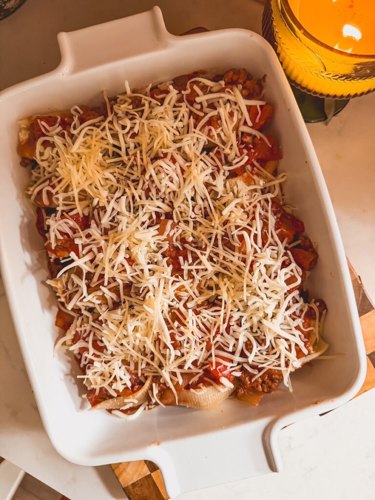 A white baking dish with beef and ricotta stuffed with grated parmesan cheese before baking.