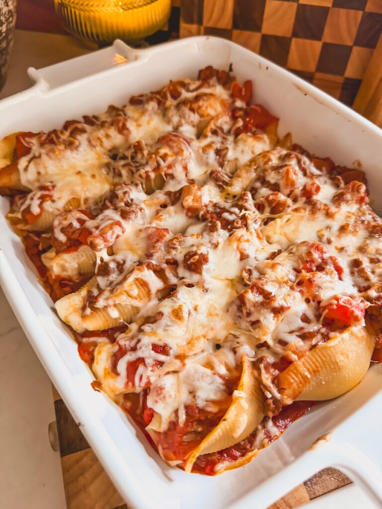 A white baking dish with beef and ricotta stuffed shells.