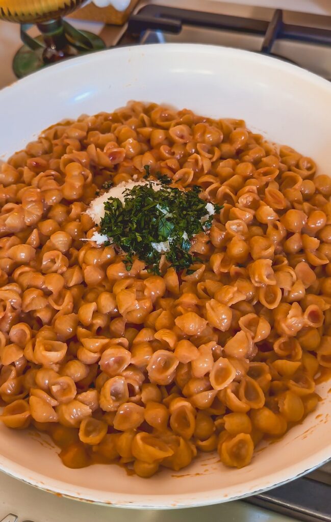 adding parmesan cheese and parsley to creamy shells