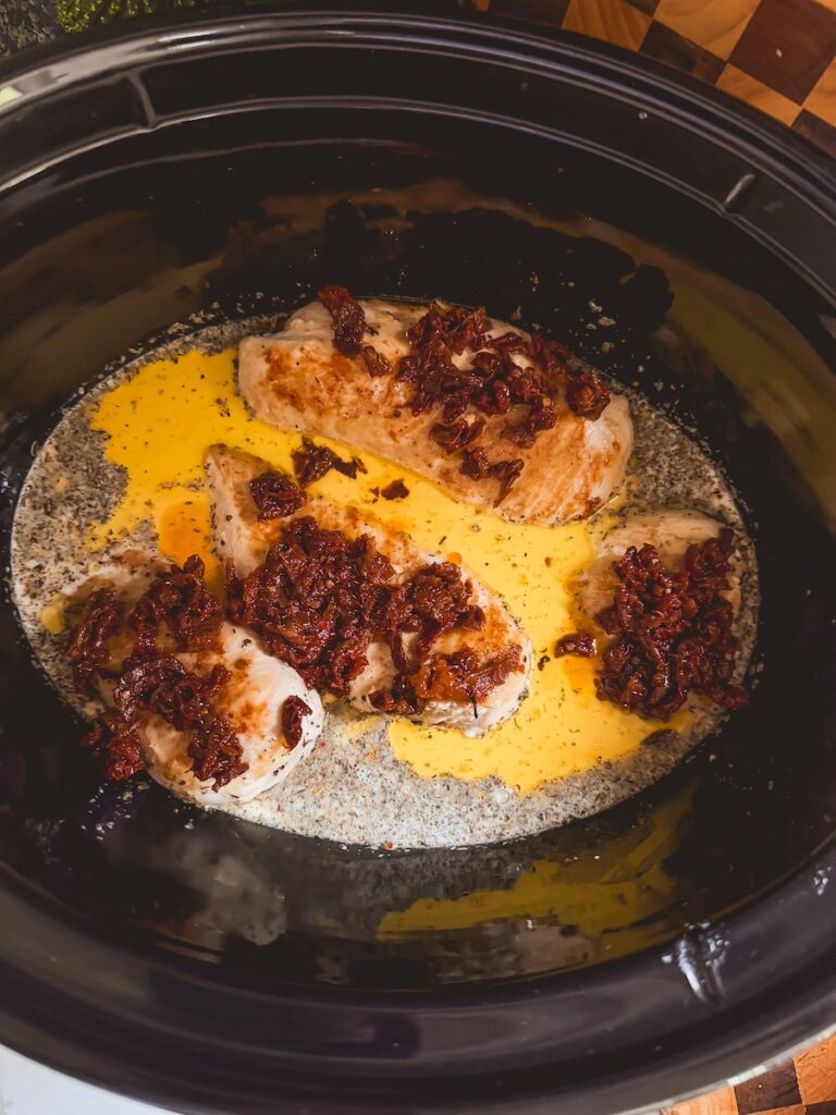 sundried tomatoes on top of the chicken in the slow cooker