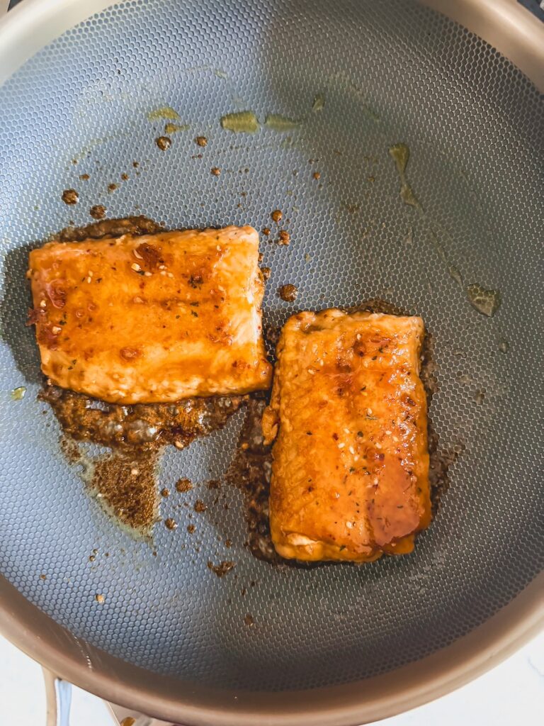 cooking the salmon on the stove top with added glaze