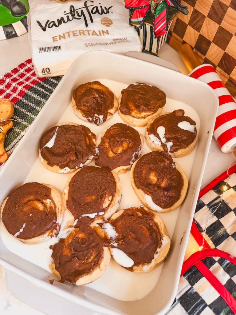 egg nog poured in the baking dish around the cinnamon rolls