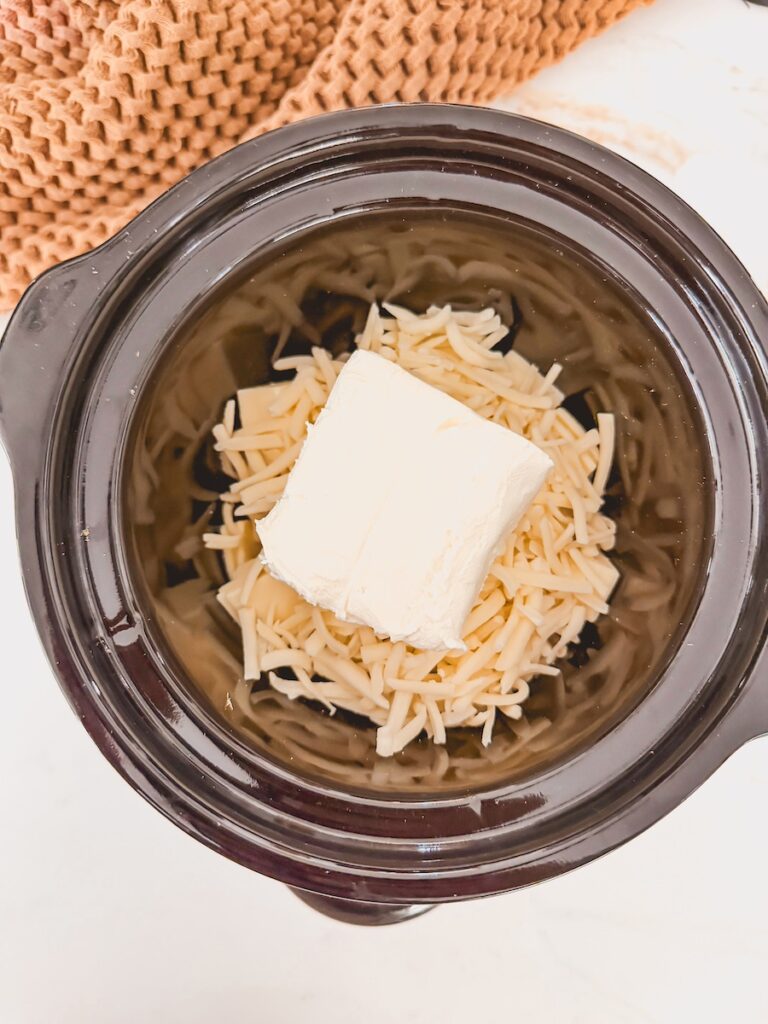 uncooked grated cheese and cream cheese in base of crock pot