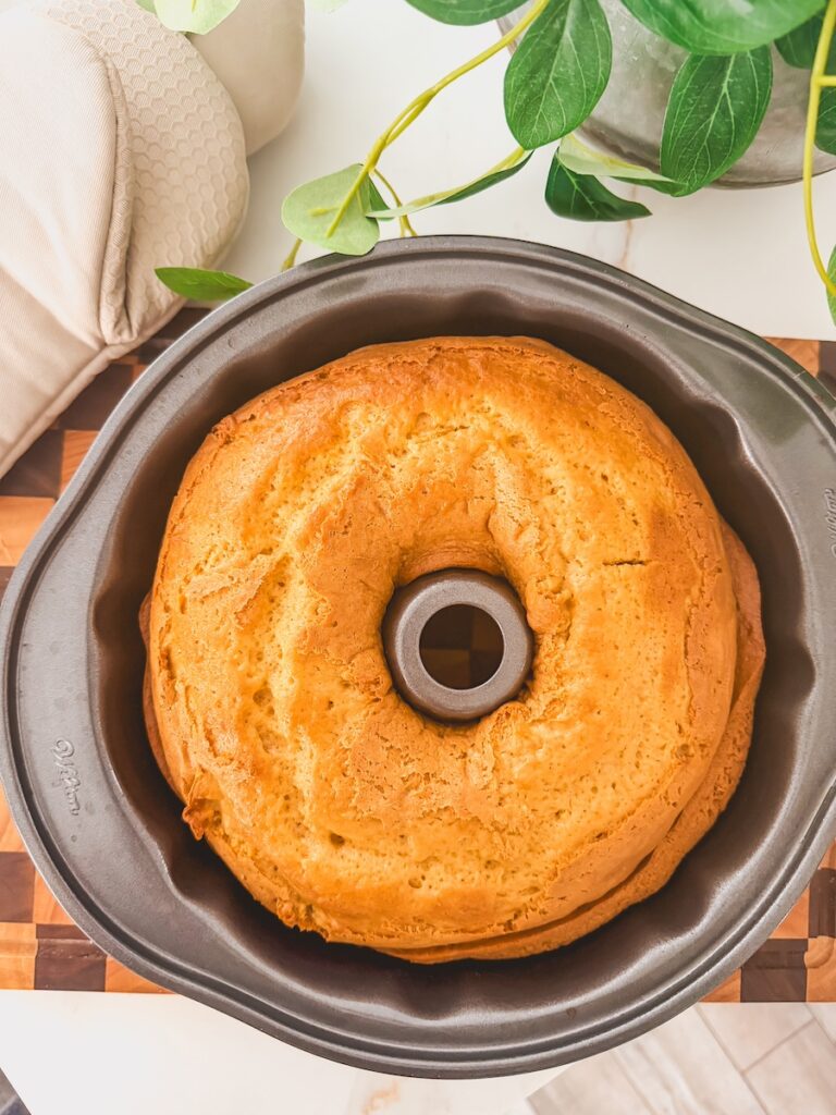 A bundt cake baked and cooling on a butting board.