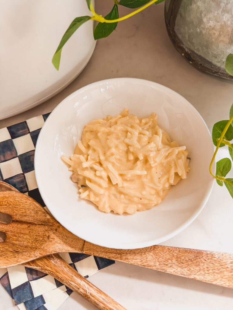cooked slow cooker cheesy potatoes in white bowl with wooden serving utensils next to it-2