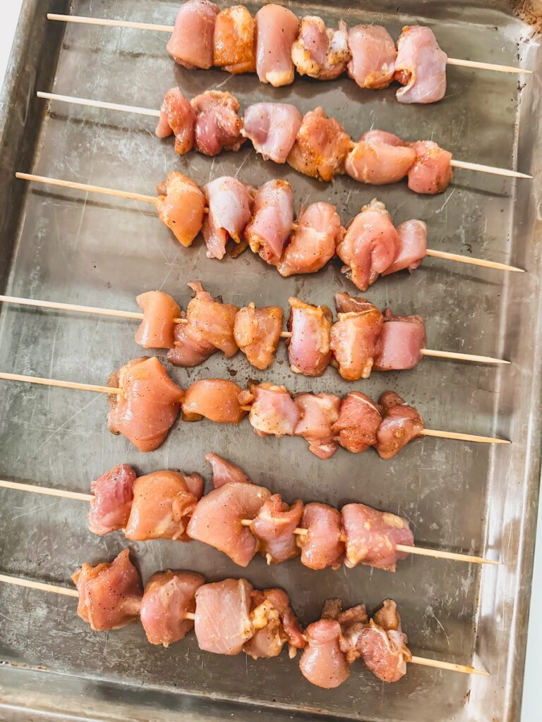 Air fryer teriyaki chicken skewers on a metal baking sheet.