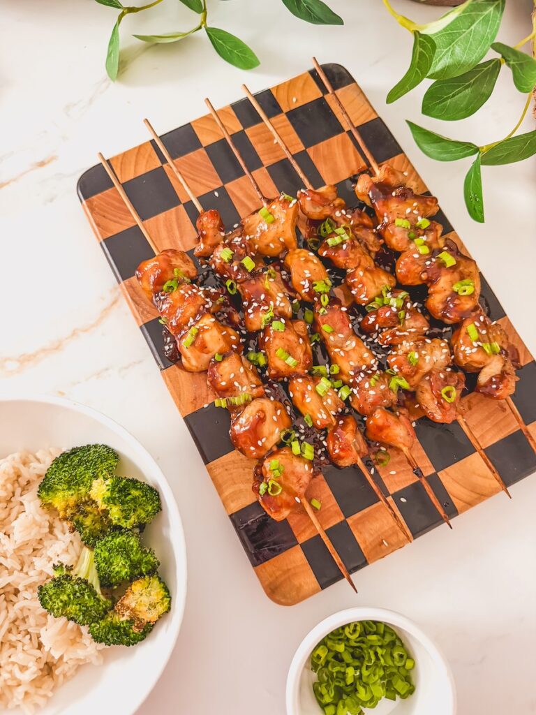 Air fryer chicken skewers on a checkered cutting board.