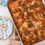 Baked croissant breakfats casserole in a baking dish with blue striped plates on the side.