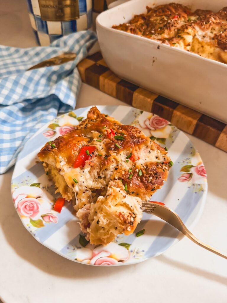 A piece of croissant breakfast casserole on a blue and white plate with a fork with a piece on it.