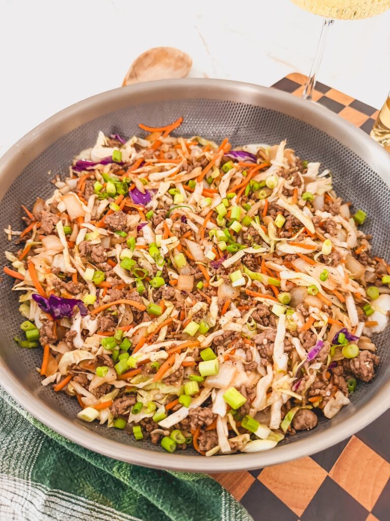 green onions on top of egg roll in a bowl in a skillet