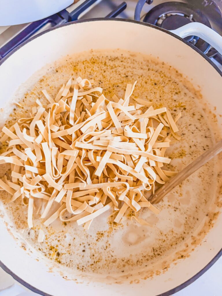 egg noodles added to soup mixture in dutch oven