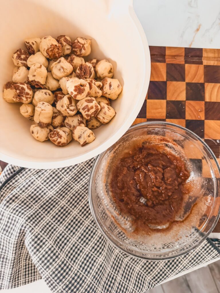 mixed glaze in clear bowl next to bowl of cinnamon roll bites