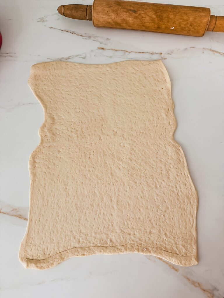 pizza dough rolled out onto surface