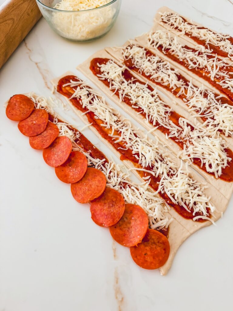 pepperoni sliced layed out onto pizza dough