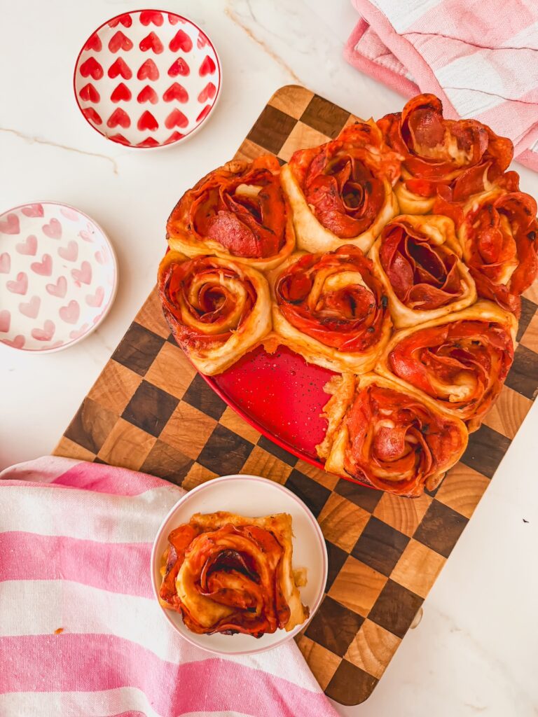 heart pizza rose on a plate next to the pan