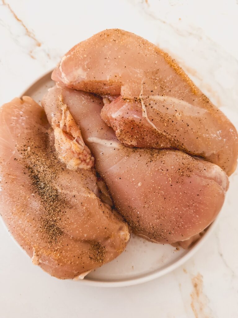 raw chicken breasts seasoned with pepper and garlic salt
