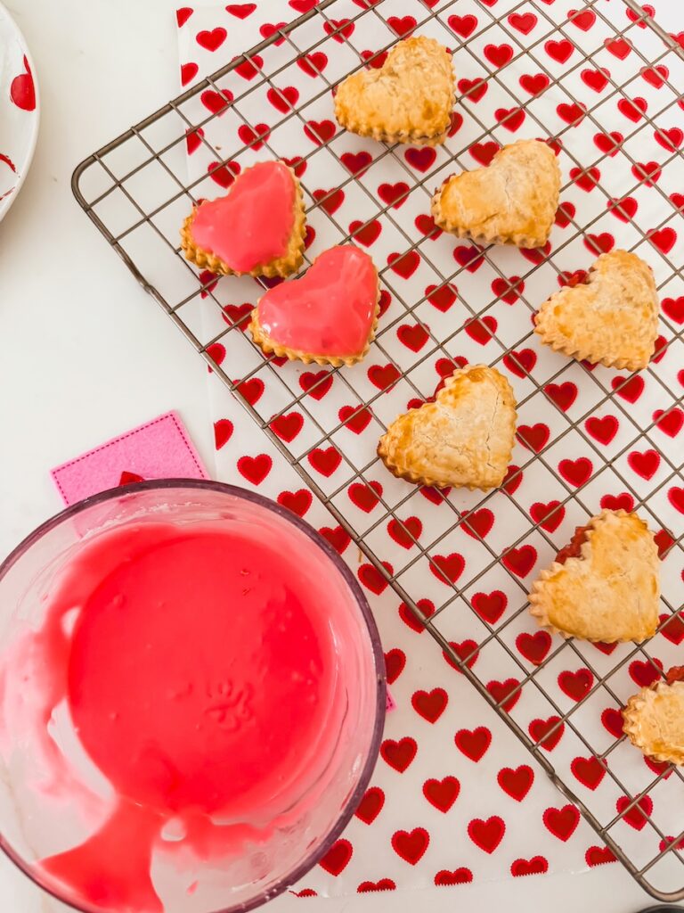 bowl of pink glaze next to heart strawberry pop tarts