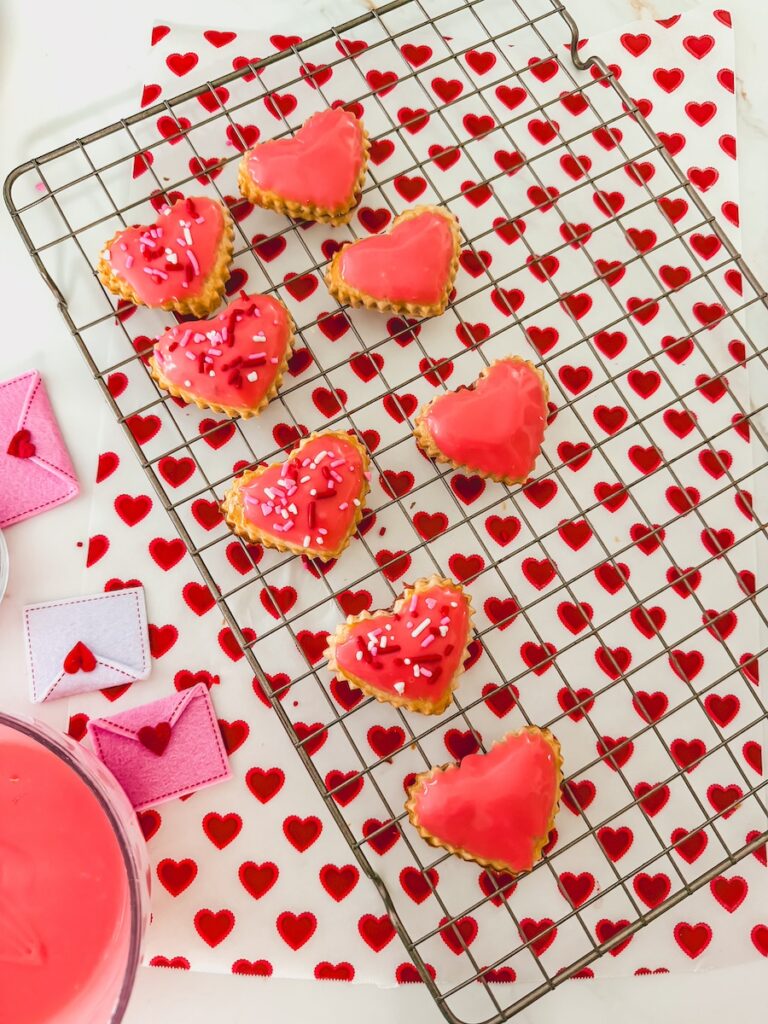 strawberry heart pop tarts laid out on baking rack with heart paper