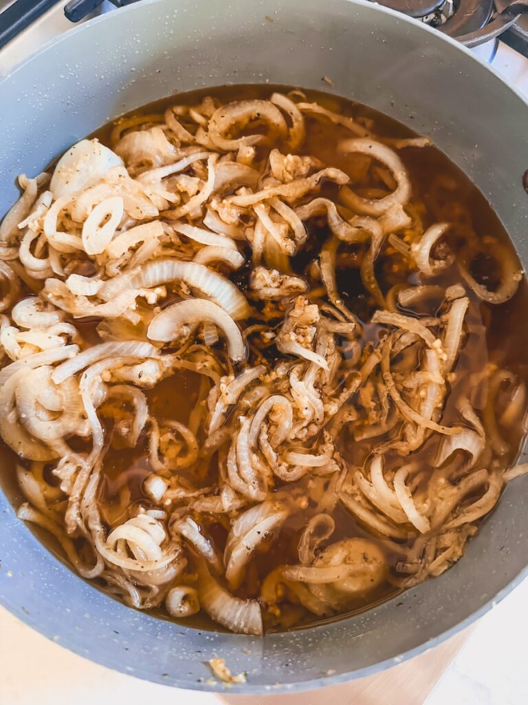 beef broth added to the pan with sautéed sliced onions
