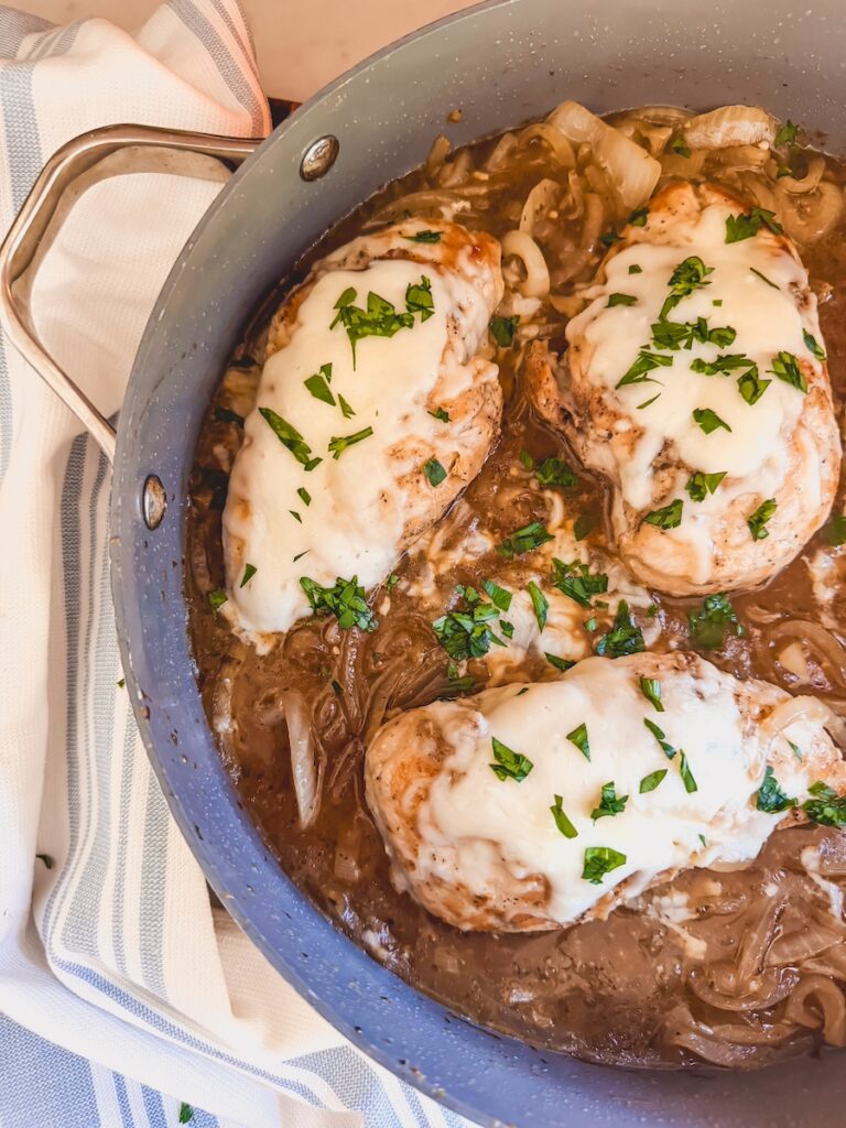 close up view of french onion chicken in pan with dish towel in background