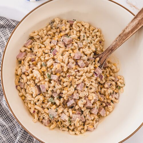 Ham pasta salad in serving bowl with serving utensil