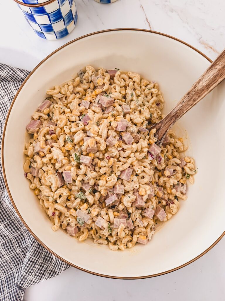Ham pasta salad in serving bowl with serving utensil