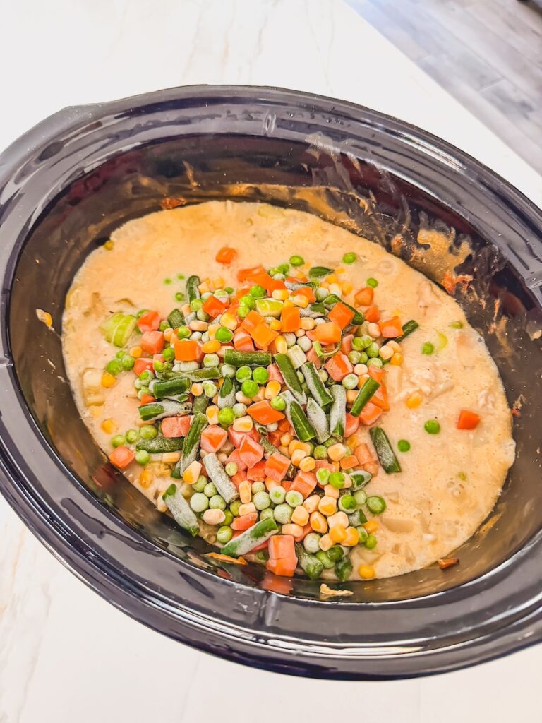 mixed vegetables added into slow cooker with the other chicken pot pie ingredients already in slow cooker.