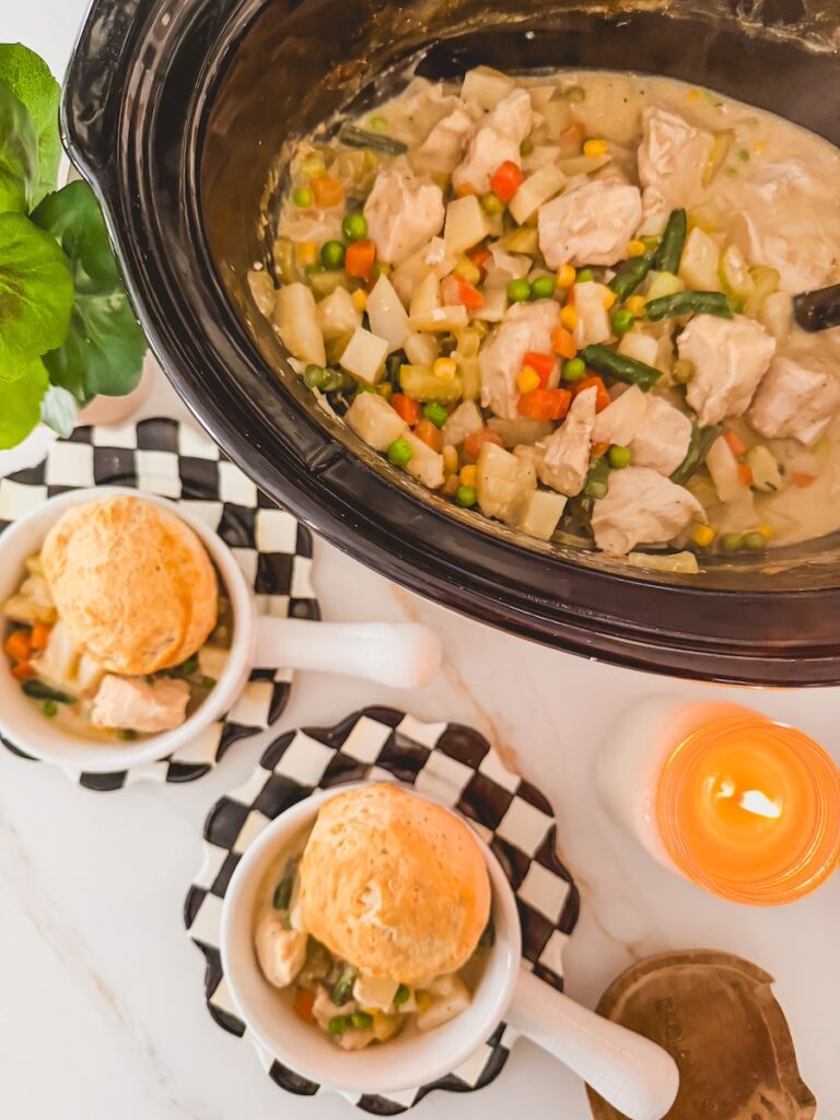 slow cooker chicken pot pie in crockpot next to two individual servings of chicken pot pie topped with biscuits