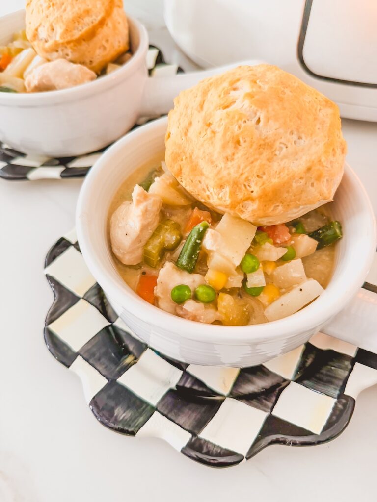 2 individual servings of chicken pot pie topped with biscuits on black and white checked saucers