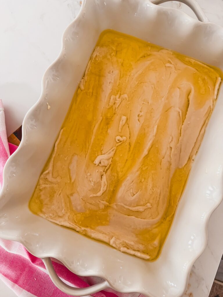 cobbler batter and melted butter in bottom of white baking dish