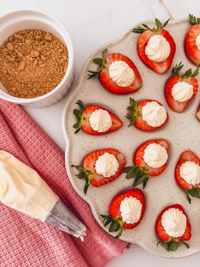 strawberries with filling next to piping bag and crushed gharam crackerers