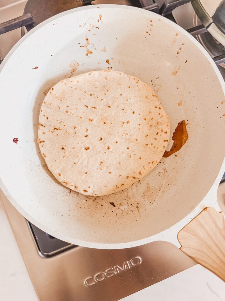 flour tortilla on skillet with ground chicken side down