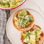 caesar salad on top of ground chicken smashed taco on white plate
