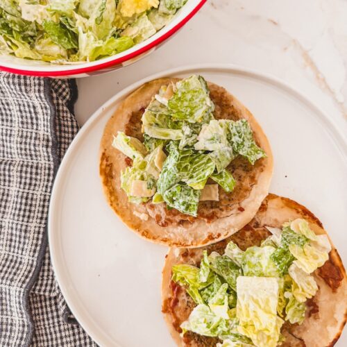 caesar salad on top of ground chicken smashed taco on white plate