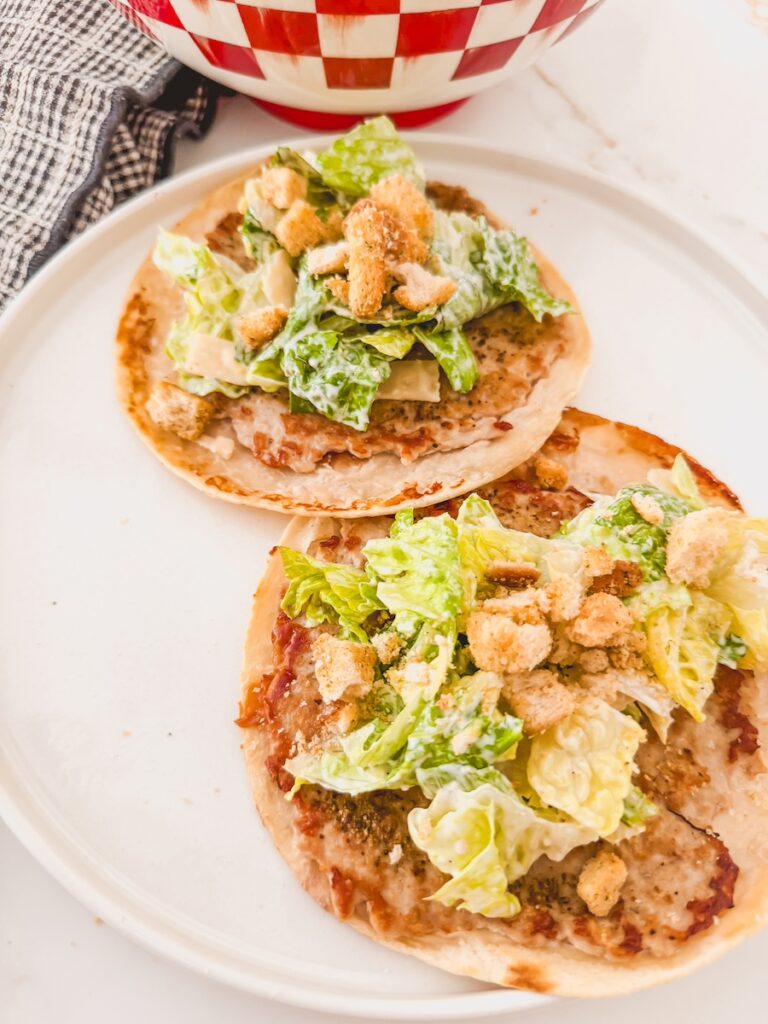 close up of smashed chicken caesar salad tacos on white plate