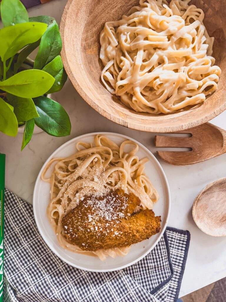 plate of pasta with tilapia along side bowl of fettuccini alfredo